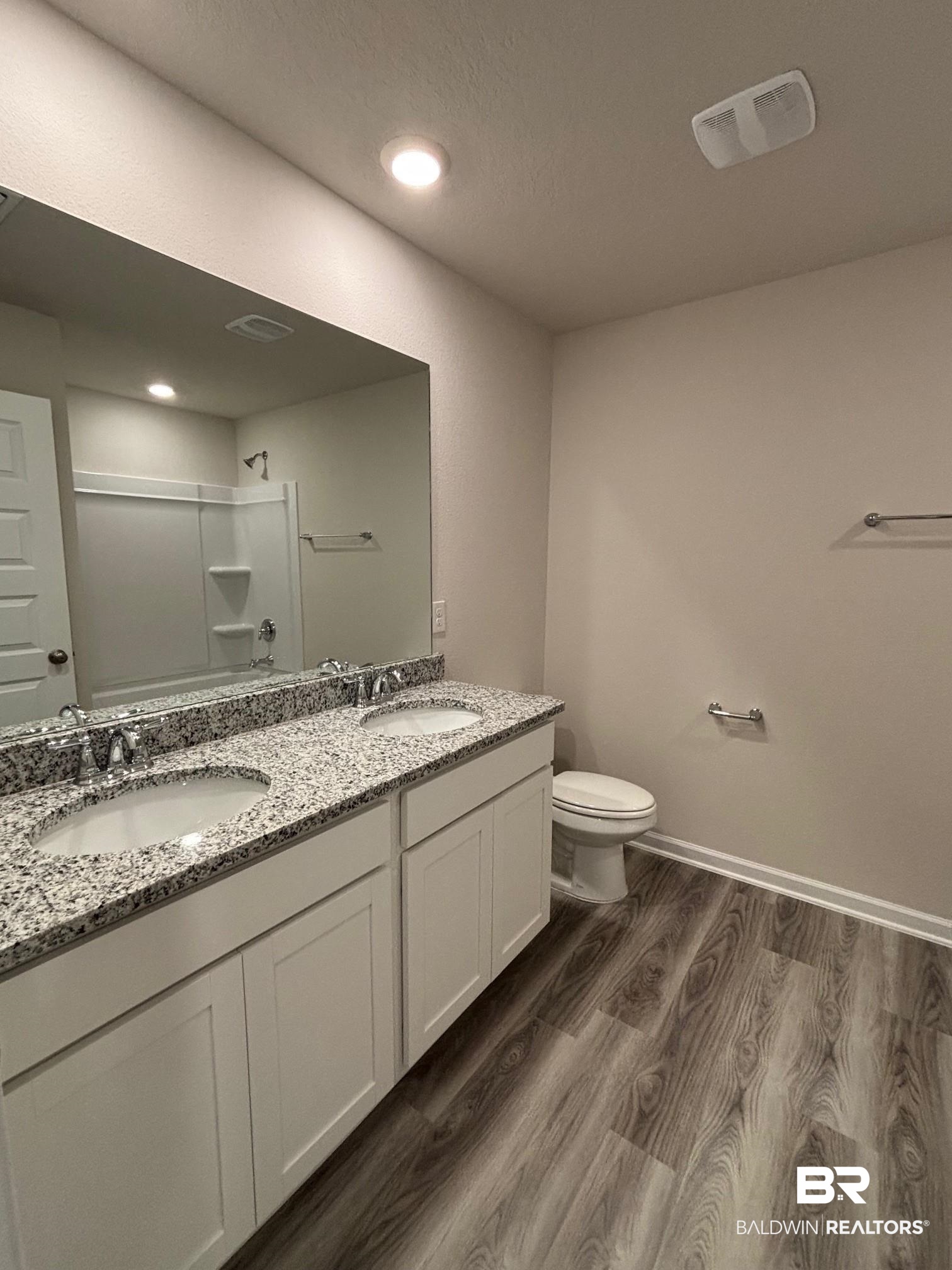 22044 Aleutian Avenue Foley, AL 36535 - Photo 11 of 28 Bathroom featuring vanity, hardwood / wood-style flooring, toilet, and a shower with door