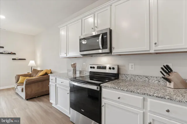 a kitchen with kitchen island granite countertop a sink and white cabinets with wooden floor