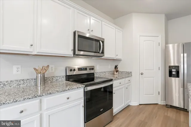 a kitchen with granite countertop cabinets stainless steel appliances and wooden floor