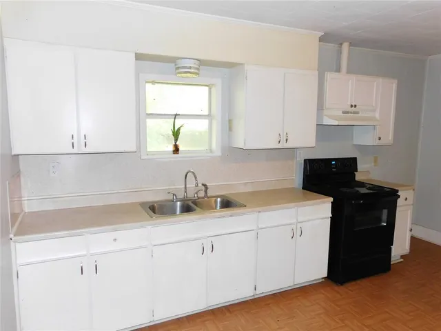 a kitchen with white cabinets and sink