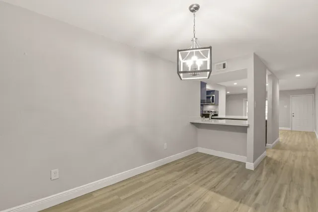 a view of a room with wooden floor and kitchen view