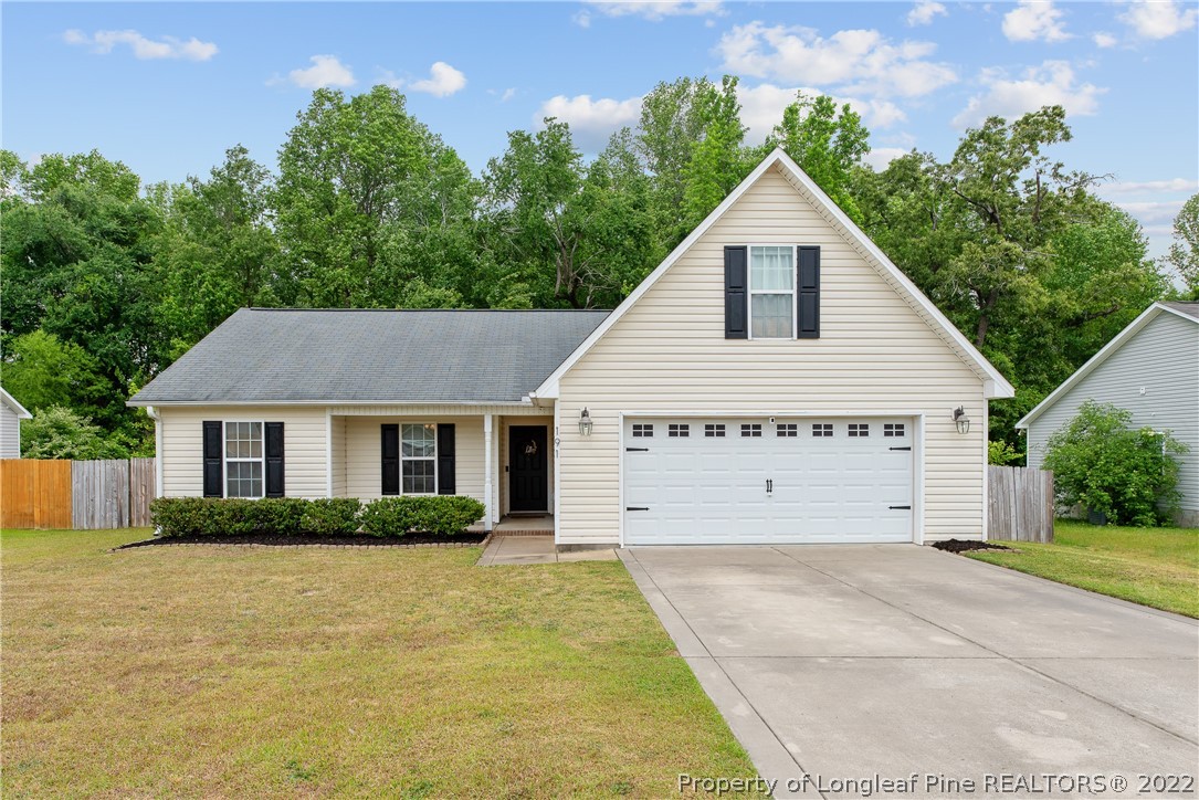 a view of a white house next to a yard with potted plants