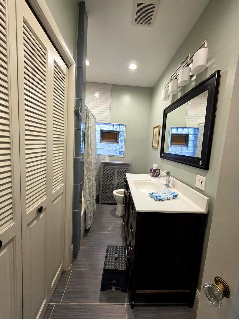 6420 North Artesian Avenue, Unit 2 Chicago, IL 60645 - Photo 5 of 8 a view of a bathroom with a sink and mirror