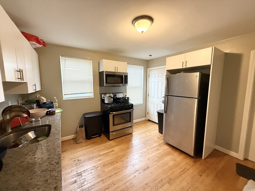 3977 Washington Street, Unit 3 Boston, MA 02131 - Photo 5 of 11 a kitchen with a refrigerator a stove a microwave and cabinets