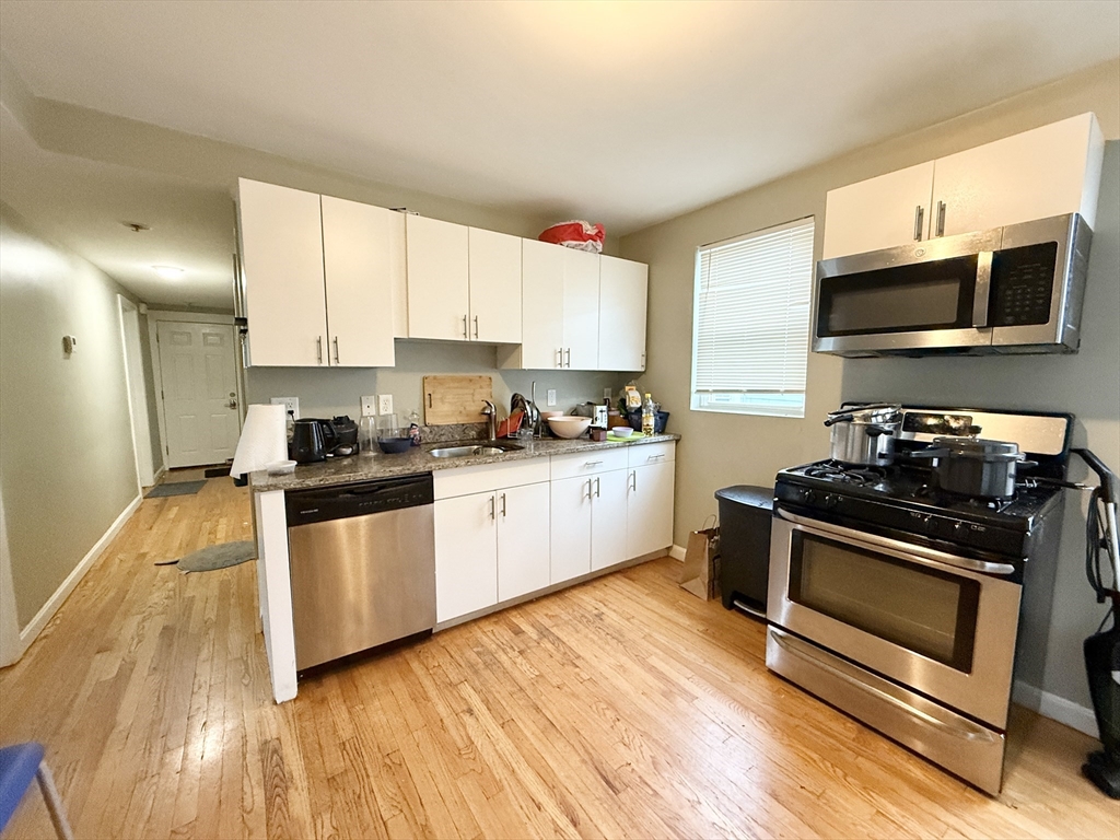 3977 Washington Street, Unit 3 Boston, MA 02131 - Photo 7 of 11 a kitchen with stainless steel appliances granite countertop a stove a sink and a microwave
