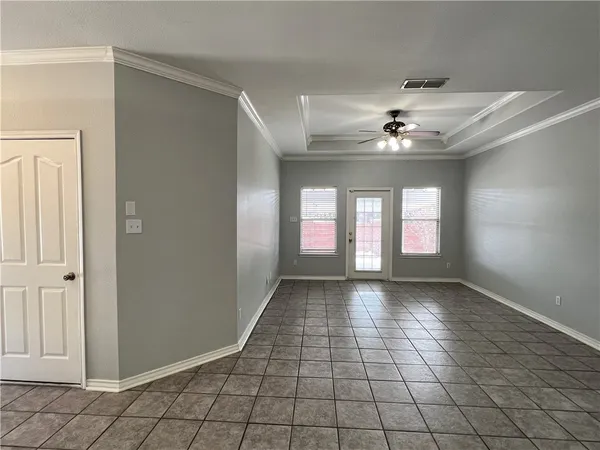 a view of an empty room with window and chandelier fan