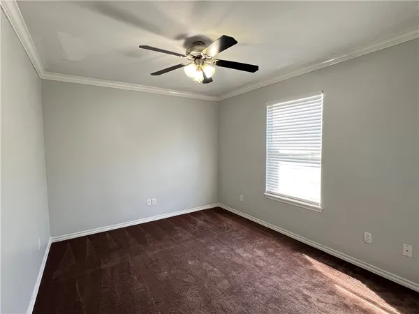 a view of an empty room with chandelier fan and a window