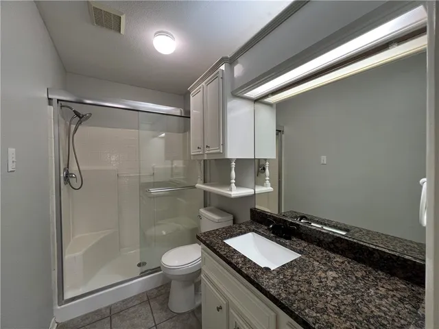 a bathroom with a granite countertop sink a toilet and shower