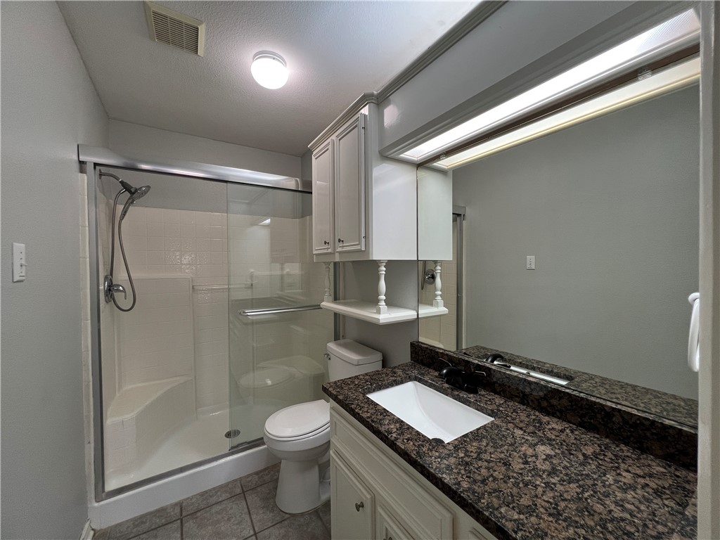 5026 Yorktown Boulevard, Unit 23 Corpus Christi, TX 78413 - Photo 17 of 29 a bathroom with a granite countertop sink a toilet and shower