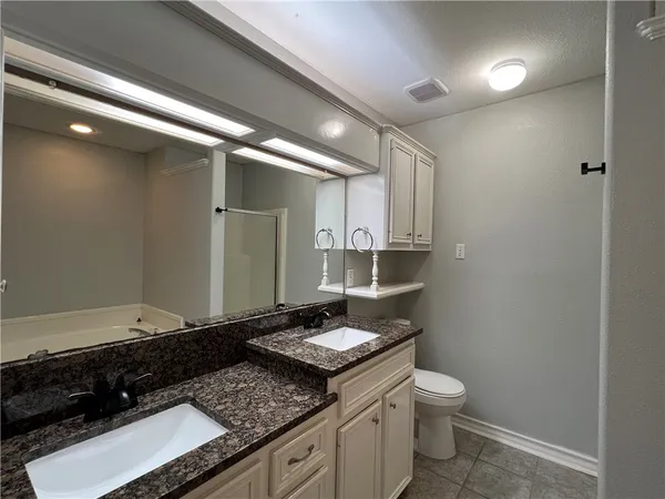 a bathroom with a granite countertop sink a toilet and a mirror