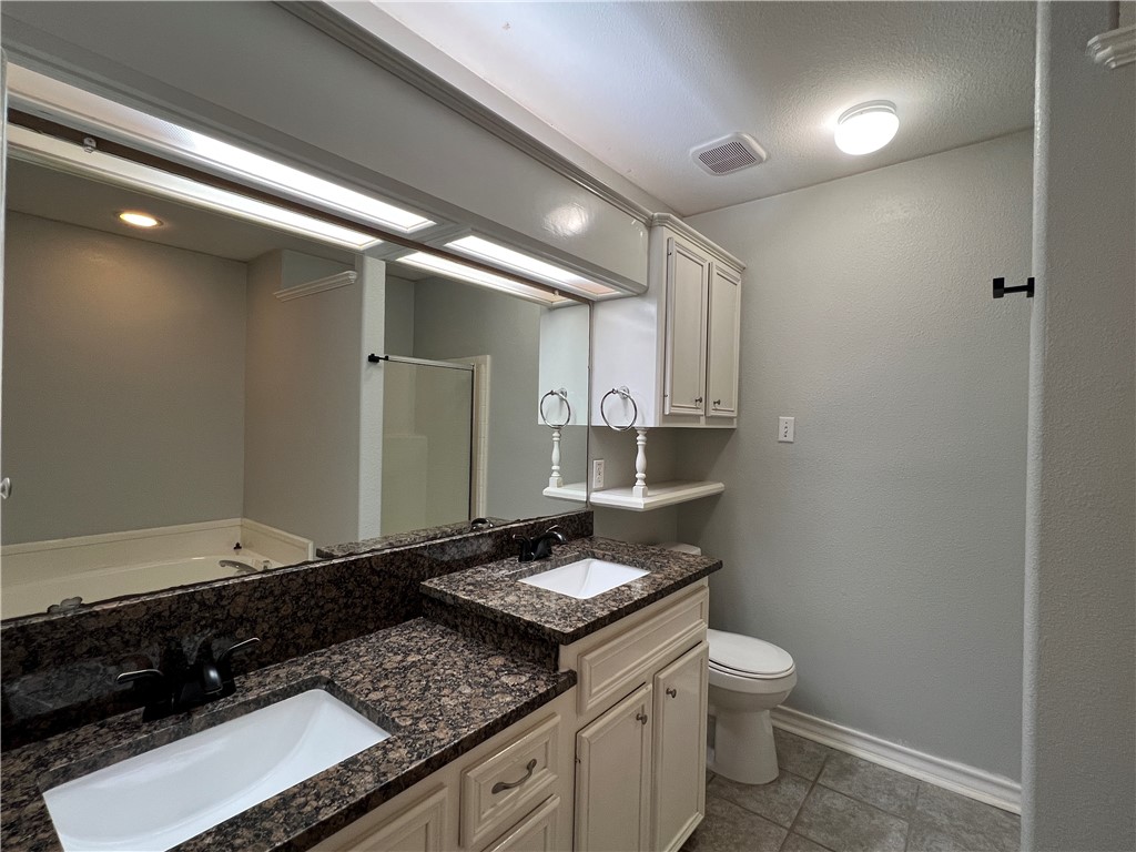 5026 Yorktown Boulevard, Unit 23 Corpus Christi, TX 78413 - Photo 22 of 29 a bathroom with a granite countertop sink a toilet and a mirror