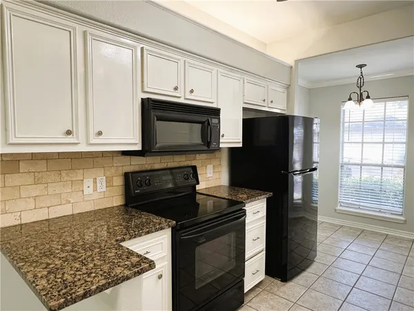 a kitchen with granite countertop a refrigerator stove and microwave