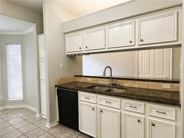 a kitchen with granite countertop white cabinets and sink