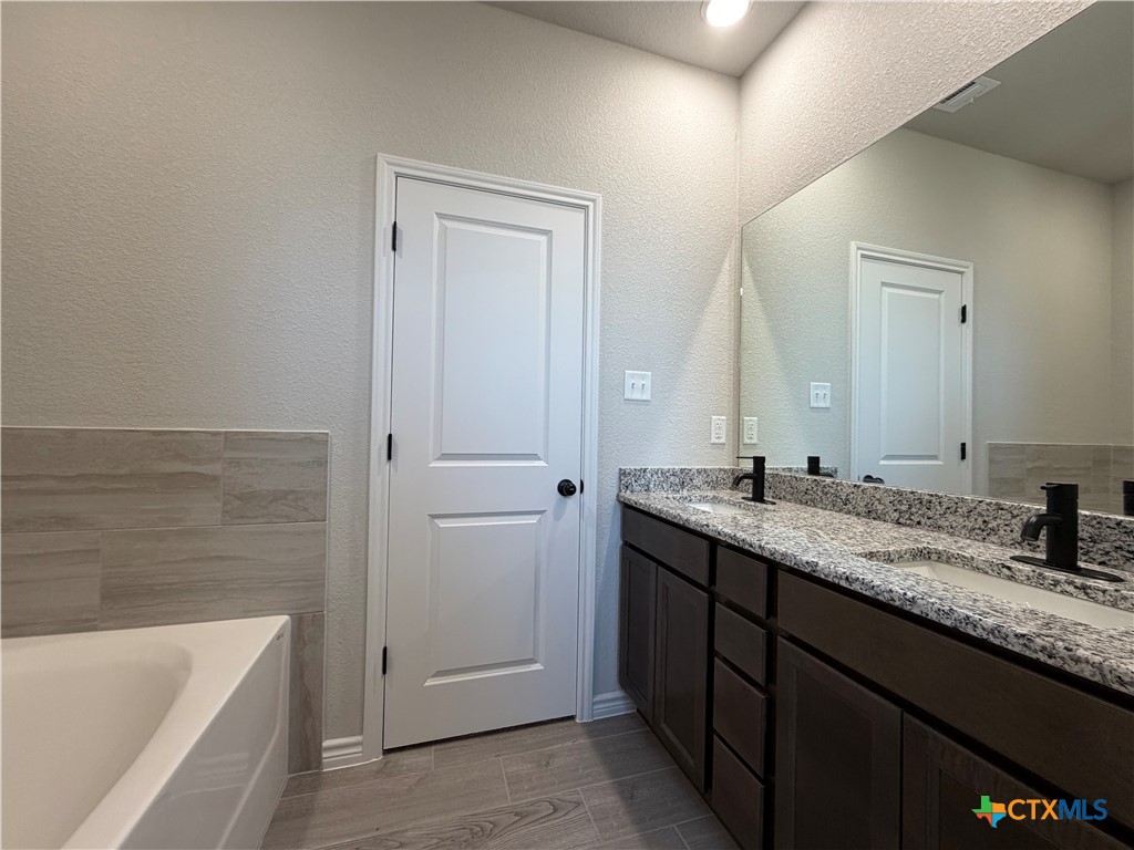 3008 Seeker Street Killeen, TX 76549 - Photo 16 of 25 a bathroom with a granite countertop sink and a bathtub