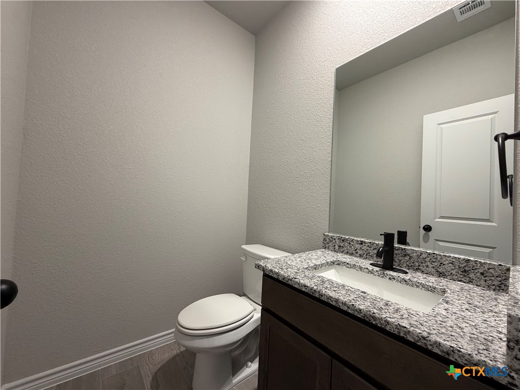 3008 Seeker Street Killeen, TX 76549 - Photo 18 of 25 a bathroom with a granite countertop sink a toilet and mirror