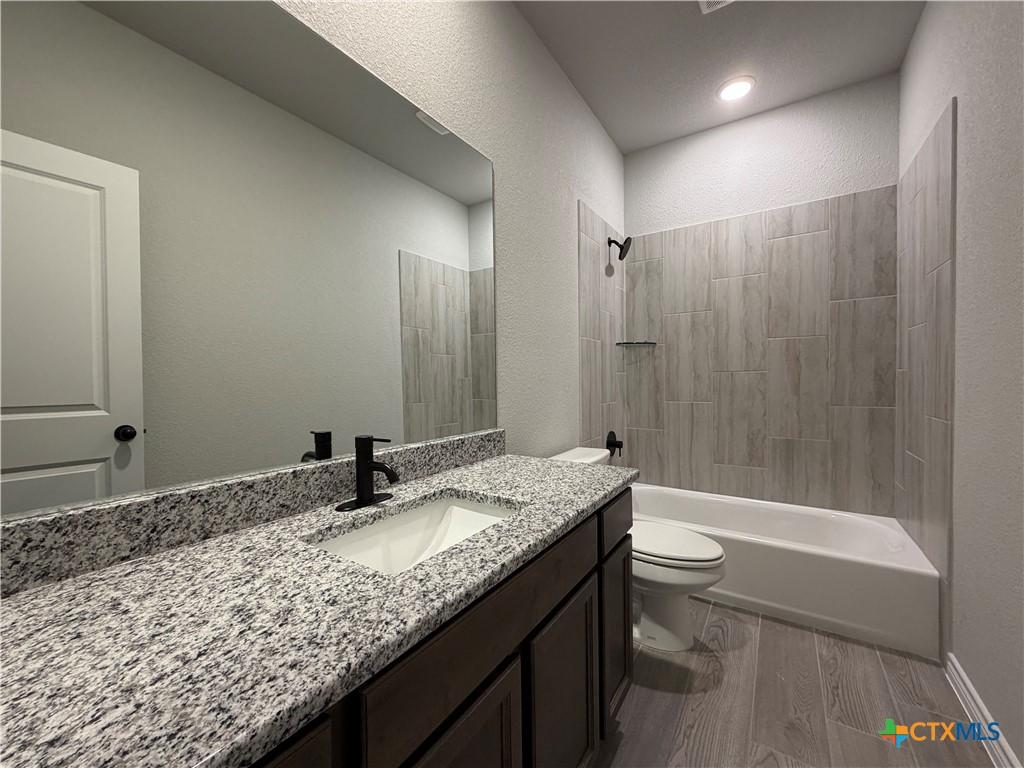 3008 Seeker Street Killeen, TX 76549 - Photo 22 of 25 a bathroom with a granite countertop sink a toilet a mirror and bathtub