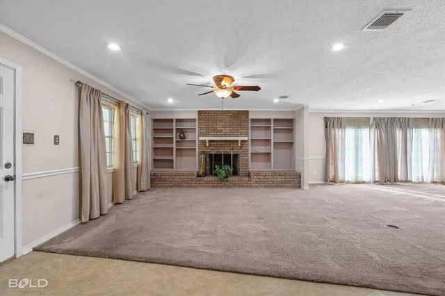 an empty room with fireplace cabinet and windows