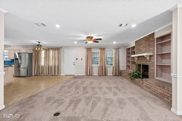a view of an empty room with fireplace and a window