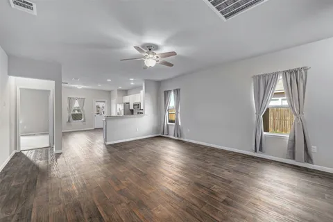a view of an empty room with a window and wooden floor