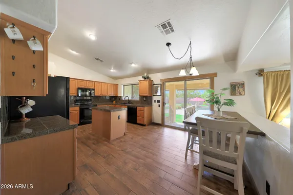a kitchen with stainless steel appliances kitchen island granite countertop a table chairs and a refrigerator