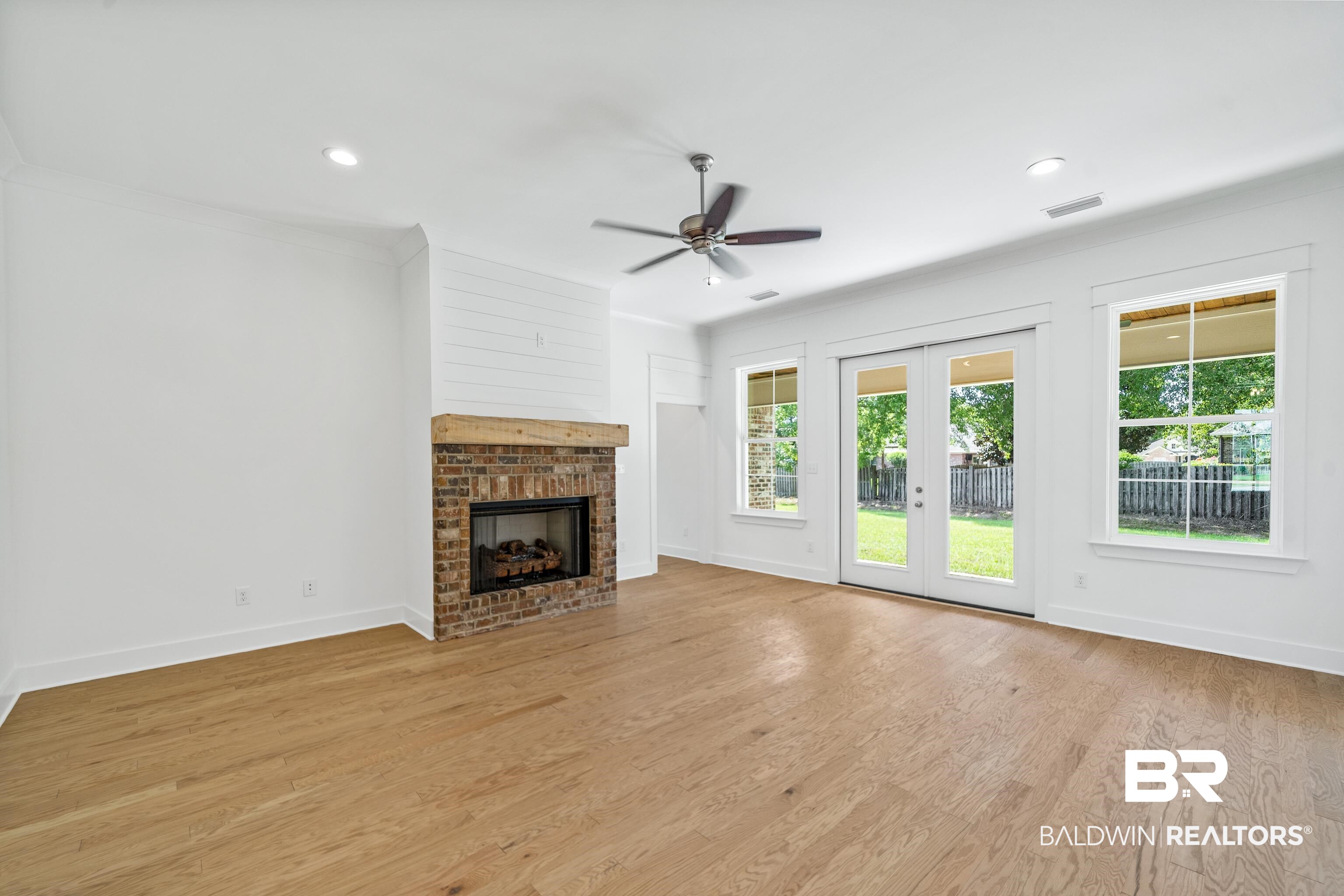 25927 Capra Court Daphne, AL 36526 - Photo 6 of 37 Unfurnished living room with a brick fireplace, light wood-type flooring, crown molding, and ceiling fan