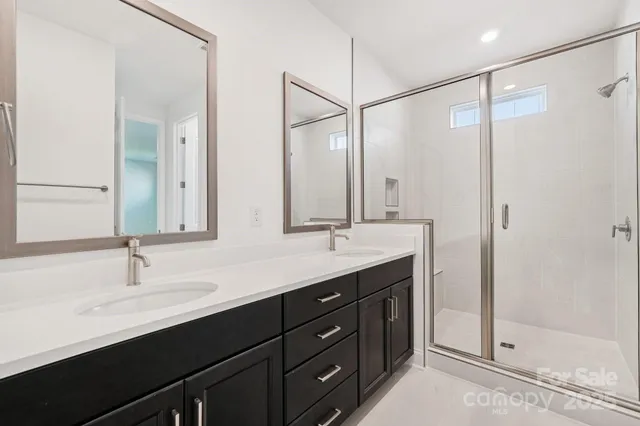a bathroom with a double vanity sink a large mirror and shower