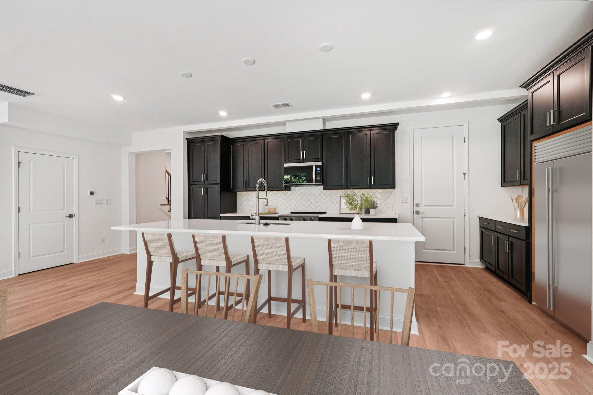620 Mercury Drive Tega Cay, SC 29708 - Photo 4 of 16 a kitchen with stainless steel appliances a dining table chairs microwave and refrigerator