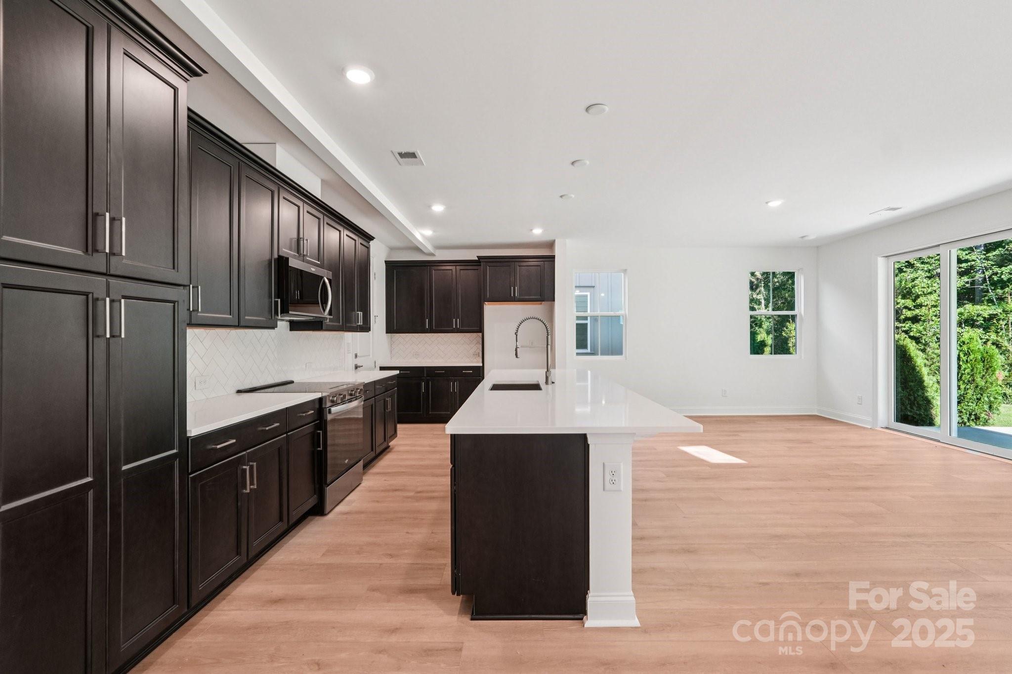 620 Mercury Drive Tega Cay, SC 29708 - Photo 5 of 16 a kitchen with stainless steel appliances kitchen island granite countertop a refrigerator a sink dishwasher and a black countertops with wooden floor