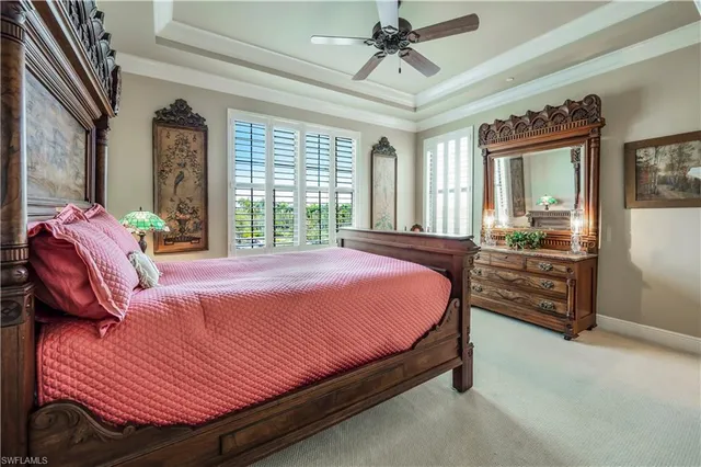 a bedroom with a bed a chandelier and dresser
