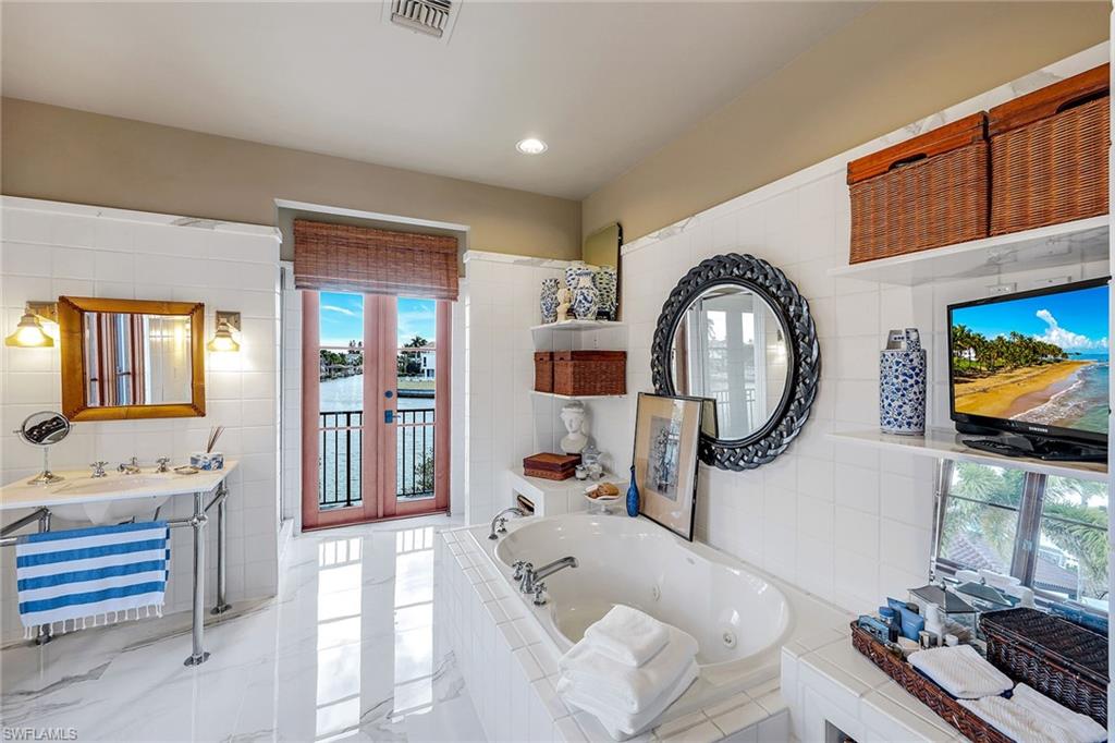 290 Channel Drive Naples, FL 34108 - Photo 30 of 49 a living room with furniture a mirror and a flat screen tv