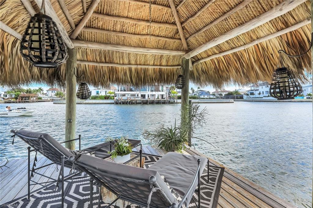 290 Channel Drive Naples, FL 34108 - Photo 45 of 45 a view of a lake with couches chairs and umbrella