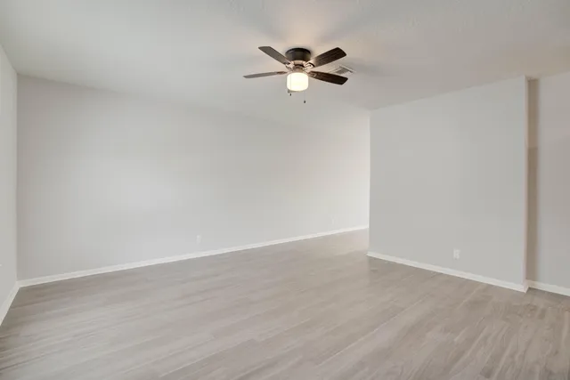 a view of a room with wooden floor and a ceiling fan
