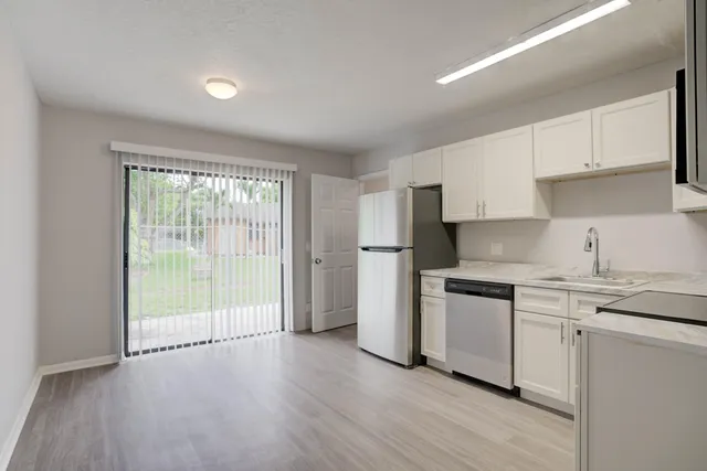 a kitchen with stainless steel appliances granite countertop a stove a sink and white cabinets with wooden floors