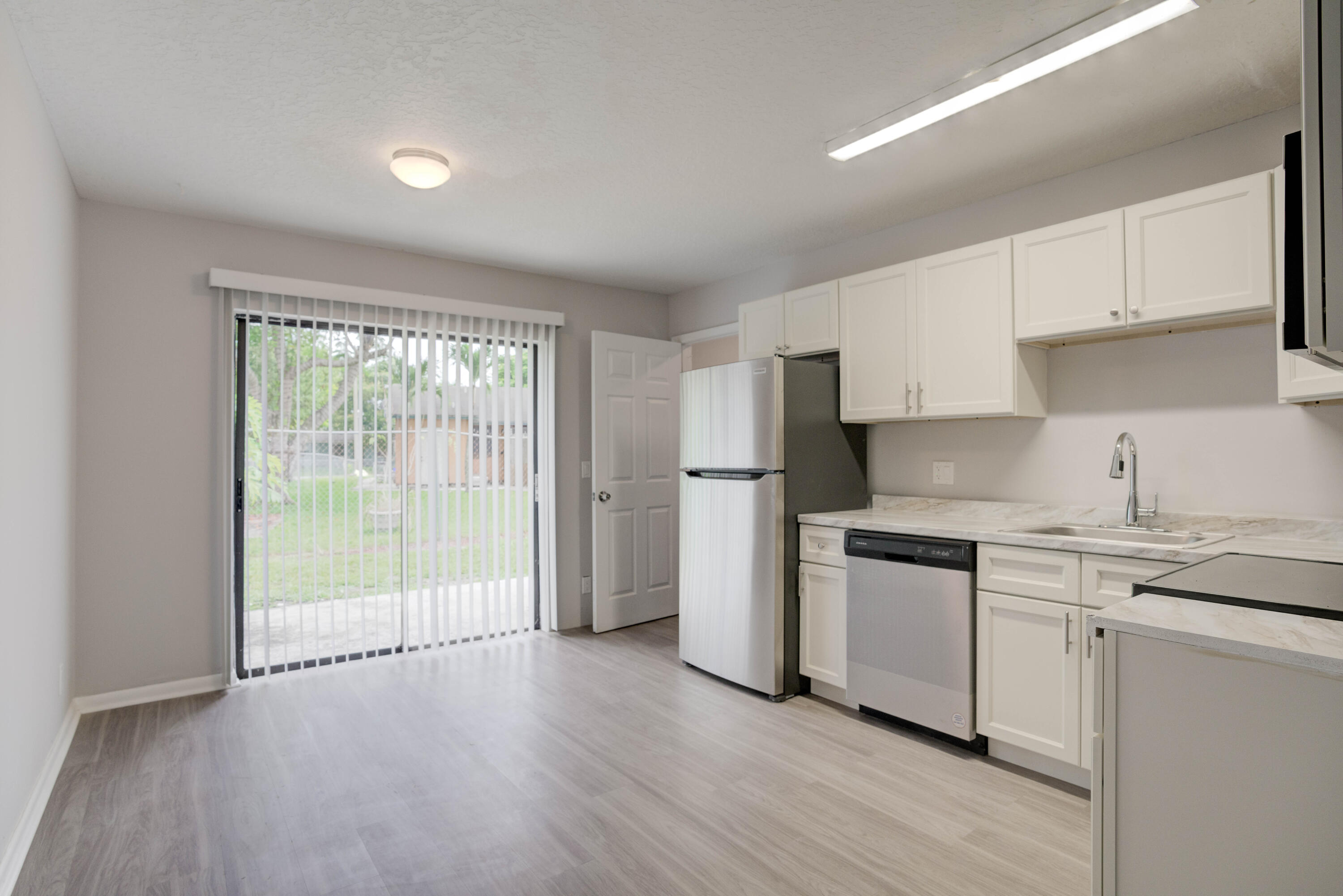 6567 Jupiter Gardens Boulevard, Unit 7 Jupiter, FL 33458 - Photo 8 of 20 a kitchen with stainless steel appliances granite countertop a stove a sink and white cabinets with wooden floors