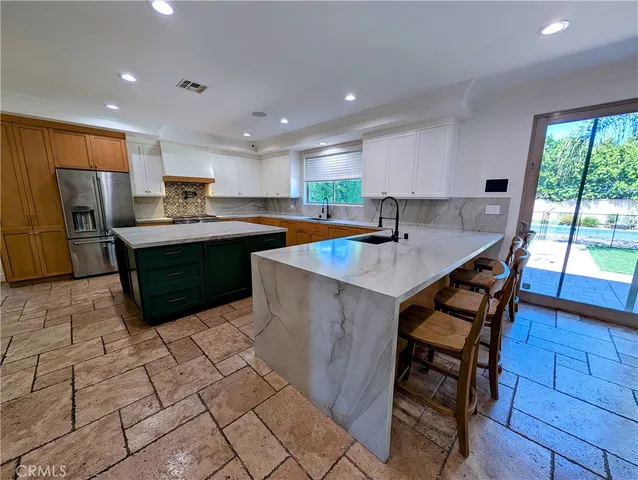 a kitchen with stainless steel appliances granite countertop a table chairs sink and cabinets