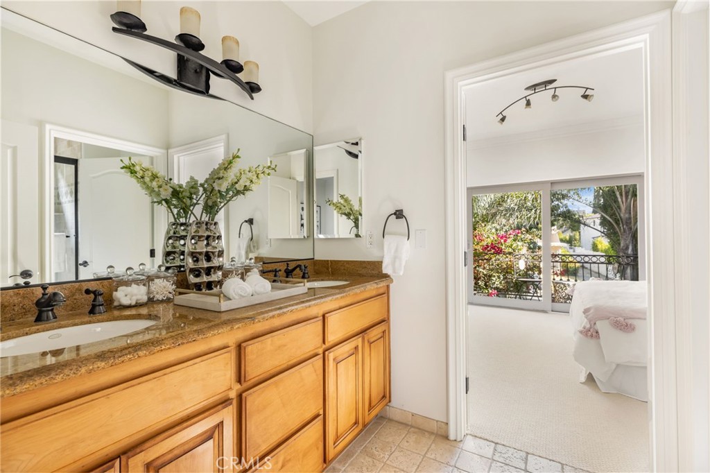 16659 Addison Street Encino, CA 91436 - Photo 28 of 48 a bathroom with a granite countertop sink mirror and window