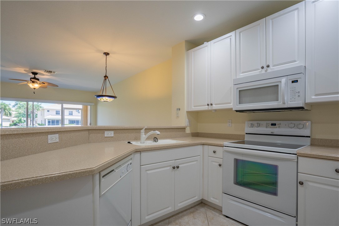 11731 Eros Road Lehigh Acres, FL 33971 - Photo 7 of 33 a kitchen with a sink dishwasher and white cabinets with wooden floor