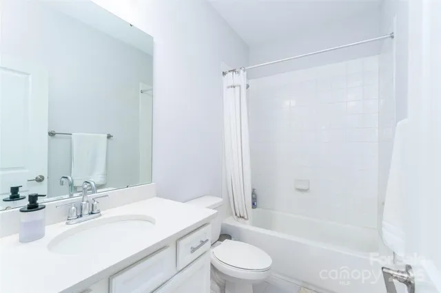 a bathroom with a granite countertop bathtub shower sink vanity mirror and toilet