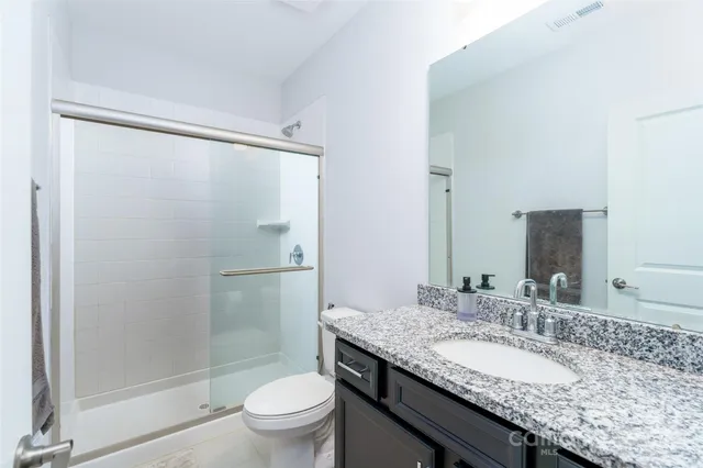 a bathroom with a granite countertop sink toilet and shower
