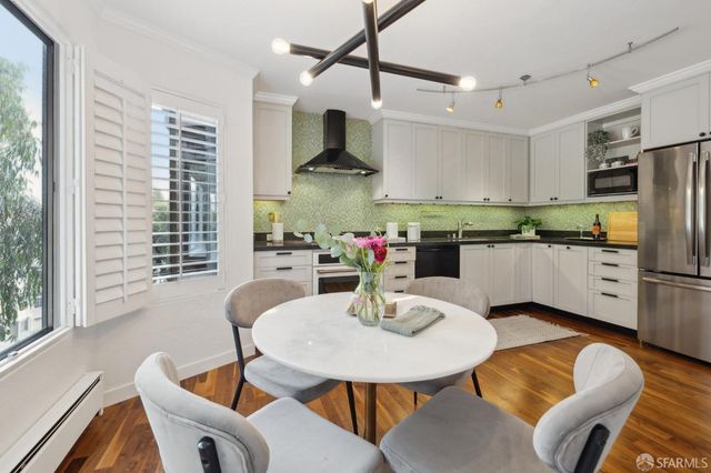 a kitchen with stainless steel appliances granite countertop a kitchen island a table and chairs in it