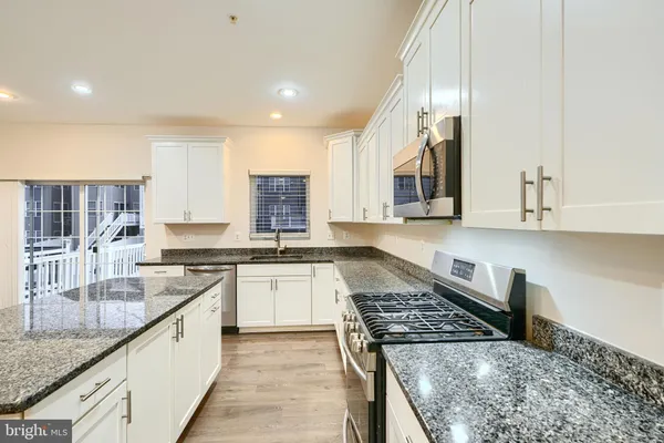 a kitchen with stainless steel appliances granite countertop a stove top oven a sink a counter space and cabinets