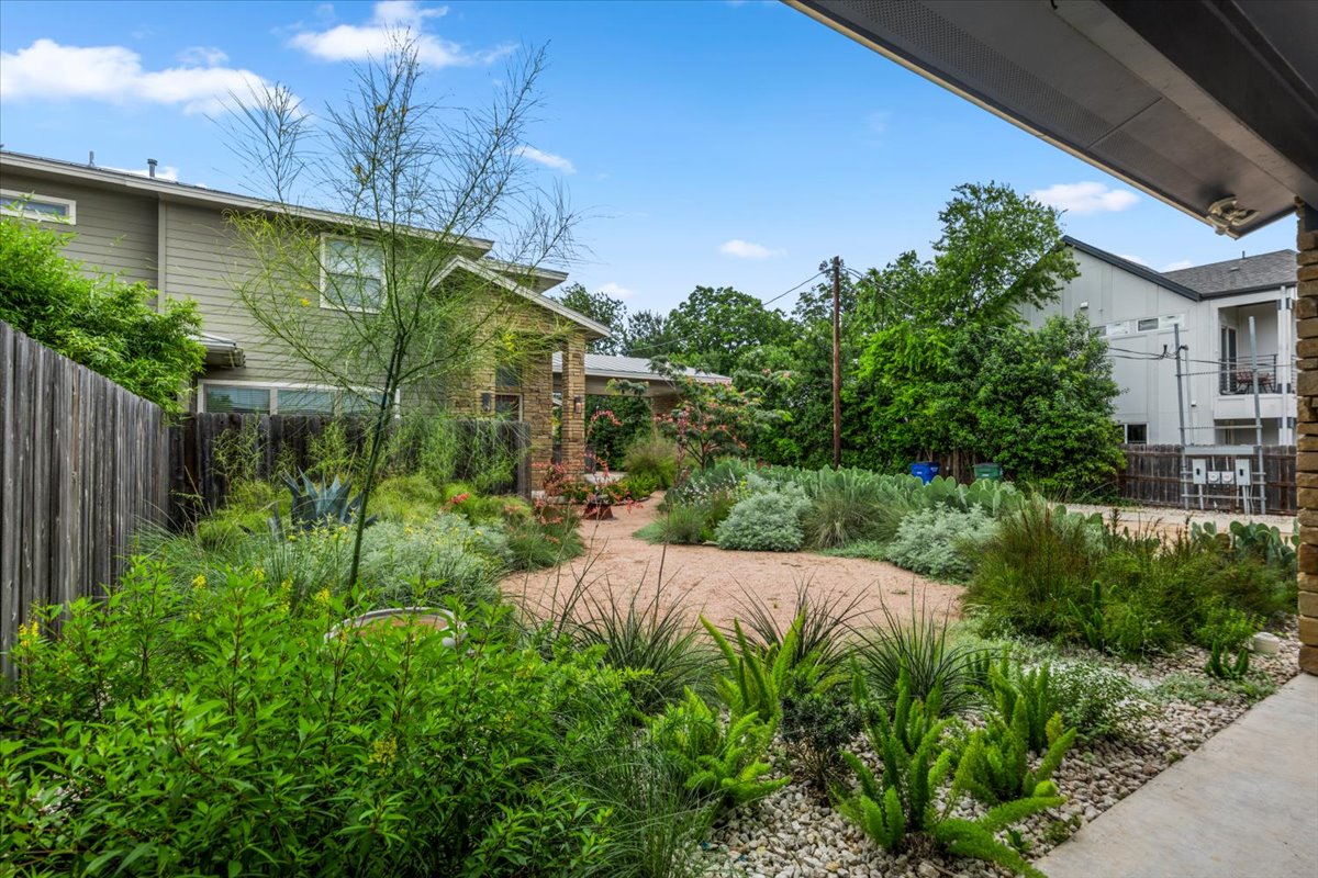 913 Stobaugh Street, Unit B Austin, TX 78757 - Photo 9 of 40 A verdant, drought-tolerant landscape surrounds a charming home, offering a tranquil outdoor retreat. This space is shared with the neighbor in the background.