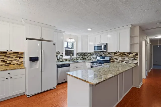 a kitchen with stainless steel appliances granite countertop a refrigerator a stove and a sink