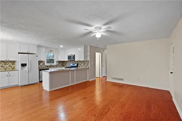 a large kitchen with stainless steel appliances granite countertop a stove a sink dishwasher and a refrigerator with wooden floor