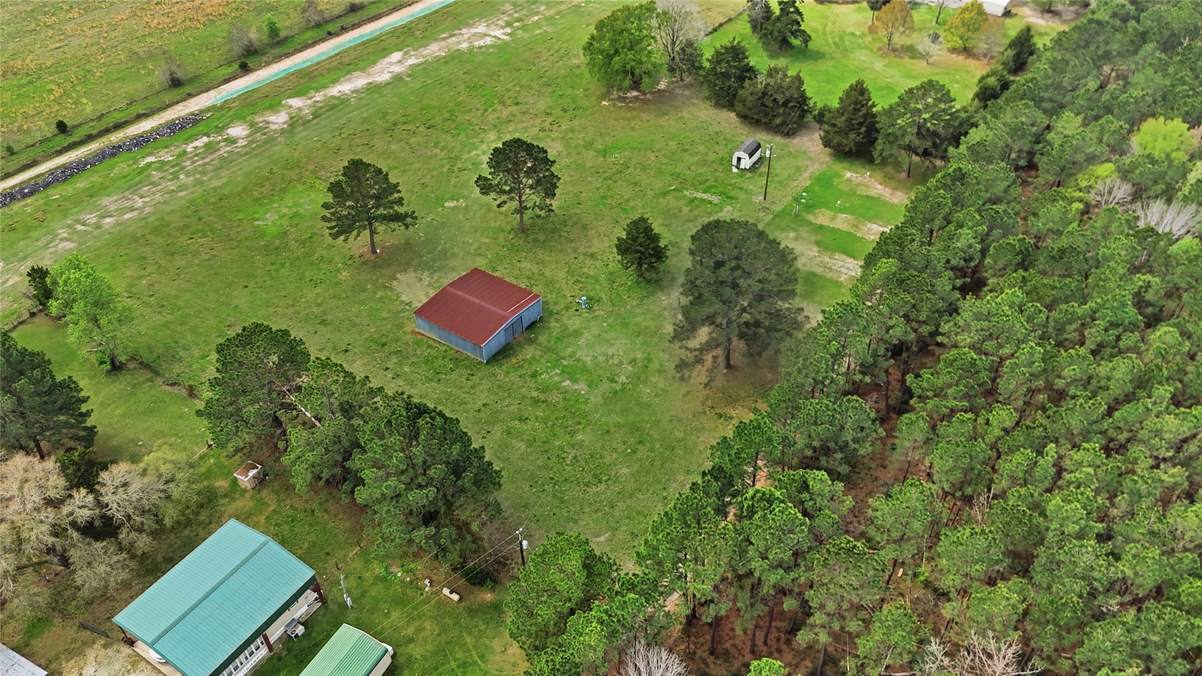 872 Four Notch Road Huntsville, TX 77340 - Photo 21 of 42 Expansive rural property with lush greenery, featuring a spacious barn and surrounded by mature trees, offering ample space and privacy.
