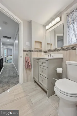 a bathroom with a granite countertop toilet sink and mirror