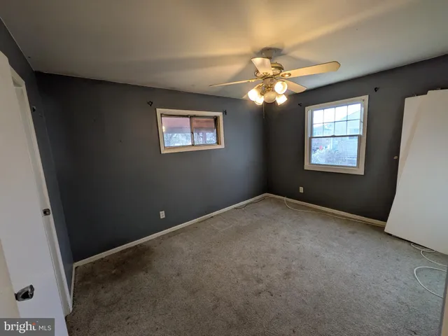 a view of an empty room with window and chandelier fan
