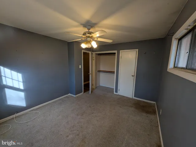 a view of empty room with window and chandelier fan