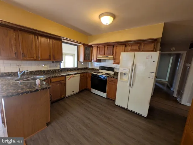 a kitchen with wooden floors and white stainless steel appliances