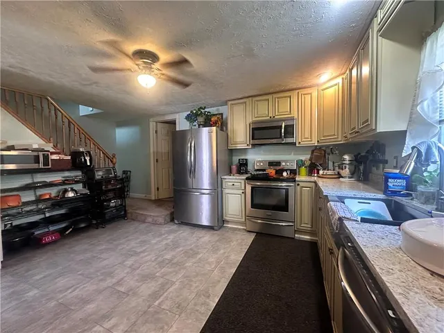 a kitchen with stainless steel appliances granite countertop a refrigerator a stove and a sink with wooden floor